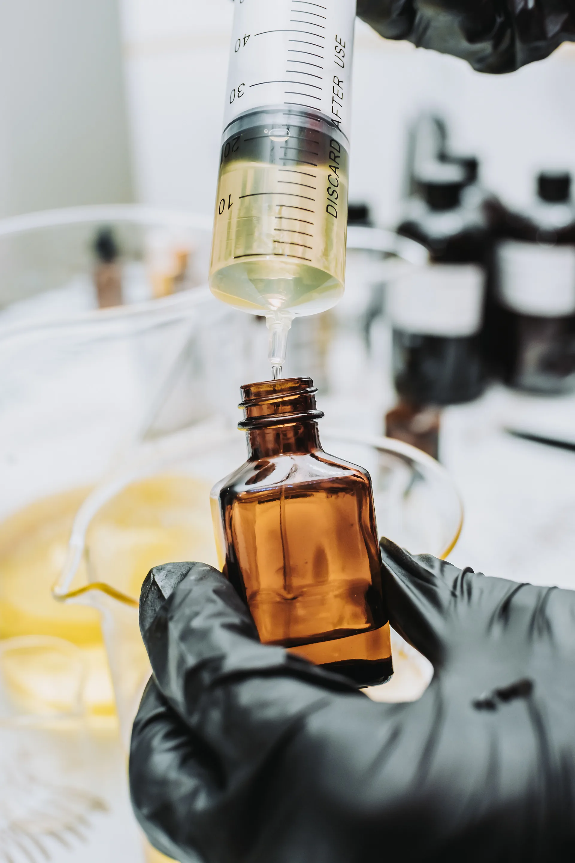Gloved hand filling an amber dropper bottle
