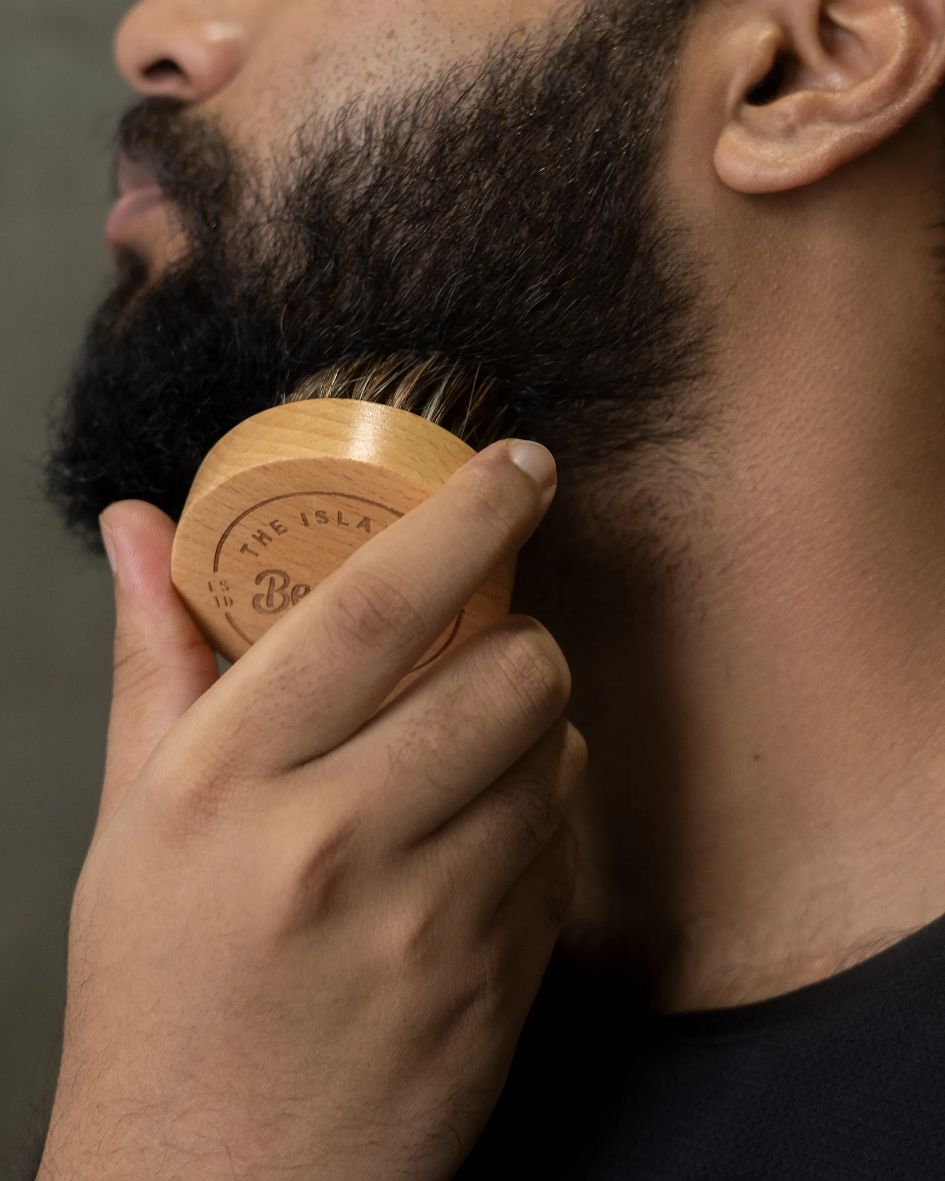 Man brushing his beard with a wooden brush